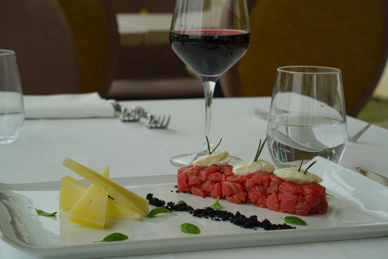 Pisa Tower Plaza Hotel Bagian luar foto A glass of red wine with a plate of tartar